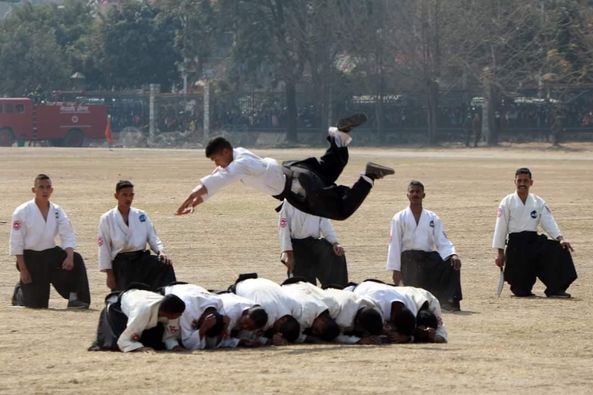 A Boy Jumping Over a Group of Men Lying